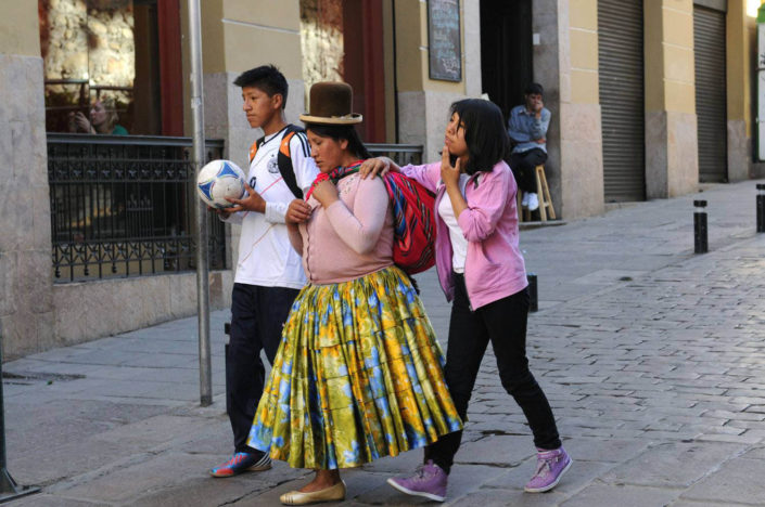 A woman in indigenous dress with her two modern-dressed adolescent children in La Paz, Bolivia.