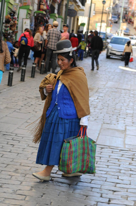 An indigenous woman wearing a traditional bowler hat and pollera (pleated skirt with petticoat), walks down the cobblestoned street Calle Sacarnaga in La Paz, Bolivia, on May 1, 2014.